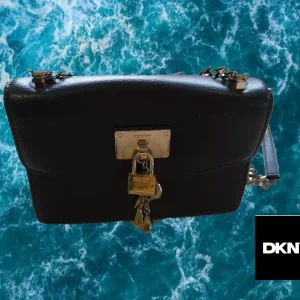 BOLSO PEQUEÑO NEGRO PIEL CON LETRAS EN FORMA LLAVERO Y CANDADO DKNY ( TARA ROCE PARTE DELANTERA Y METAL DEFECTUOSO )